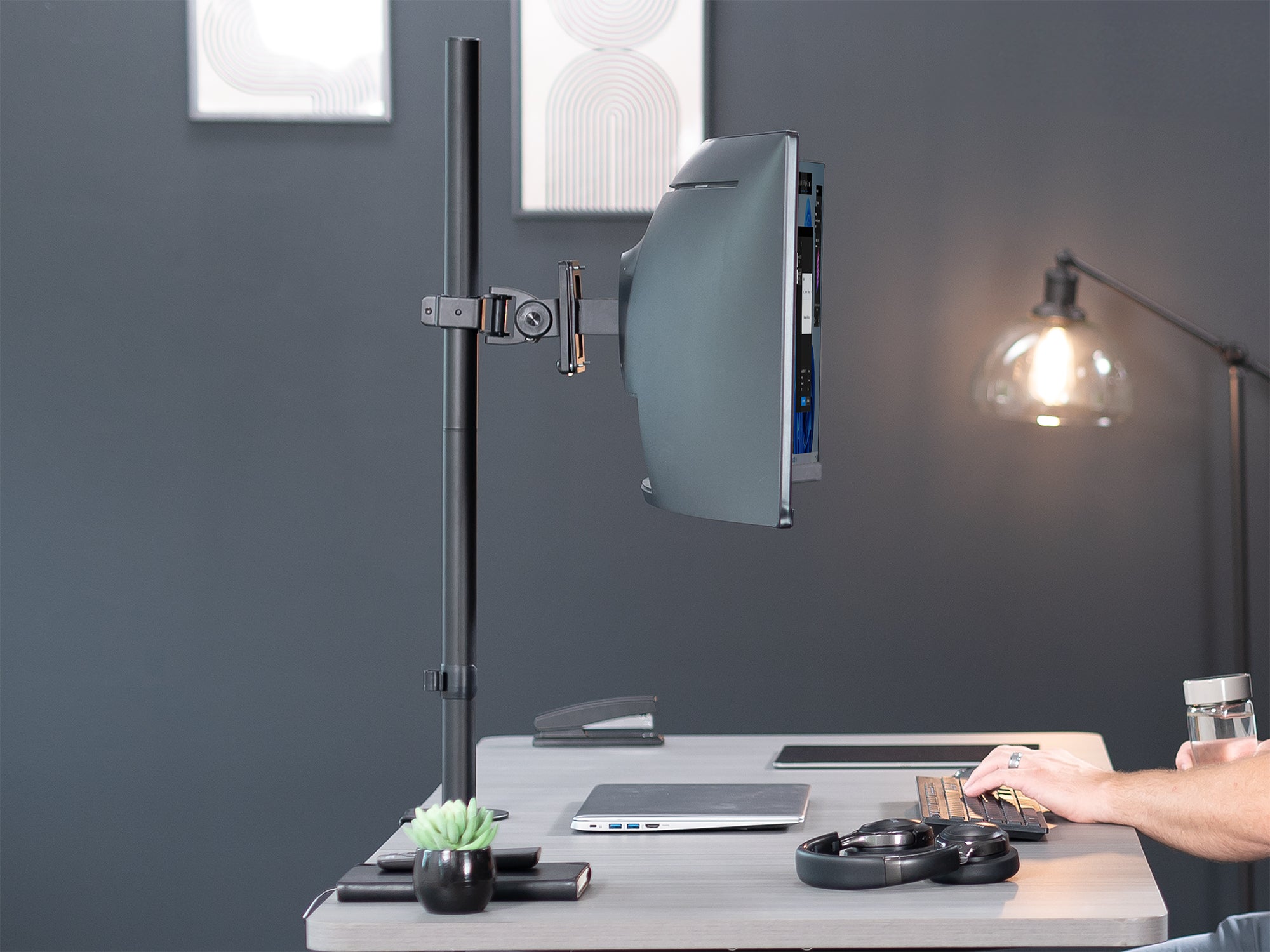model sitting at desk with ultrawide, extra tall monitor stand