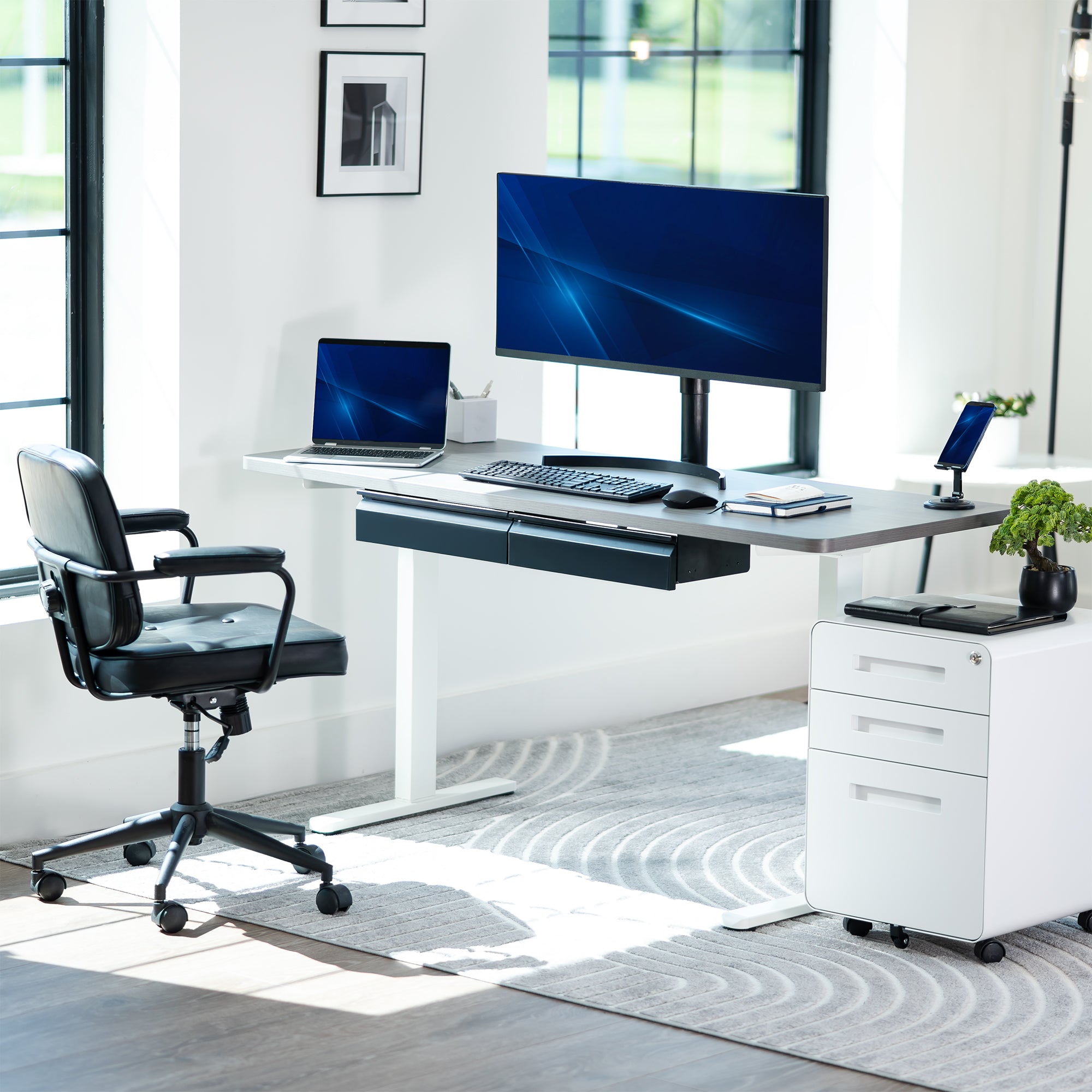 Modern office desk setup with computer monitor, keyboard, mouse, and chair in a bright room.
