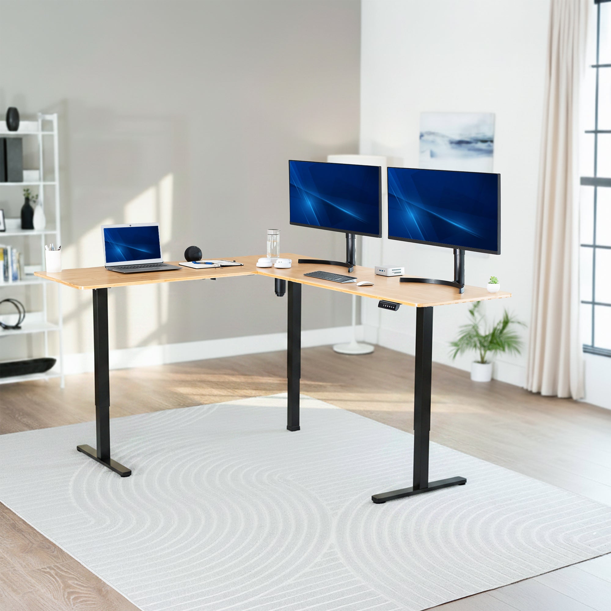 Modern home office setup with a standing l-shaped desk, laptop, and two monitors.