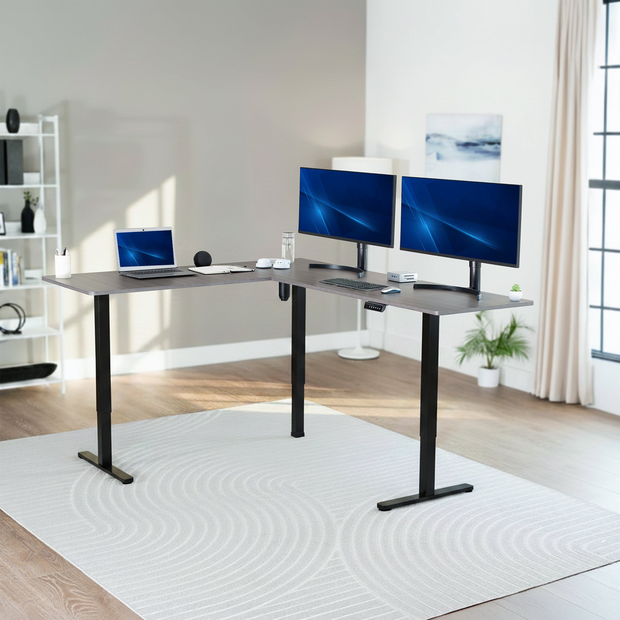 Modern home office setup with a standing l-shaped desk, laptop, and two monitors.