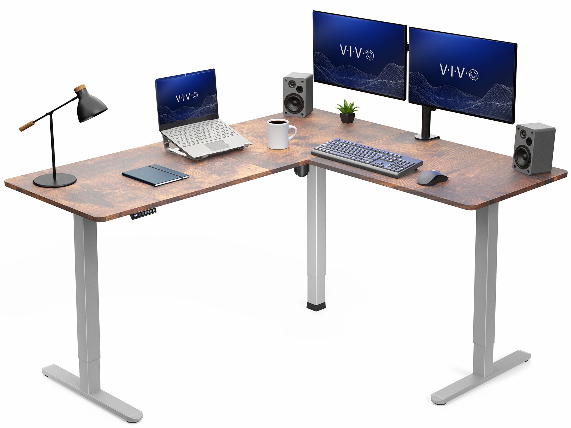 Wooden L-shaped desk with computer setup including two monitors, laptop, keyboard, and office items.