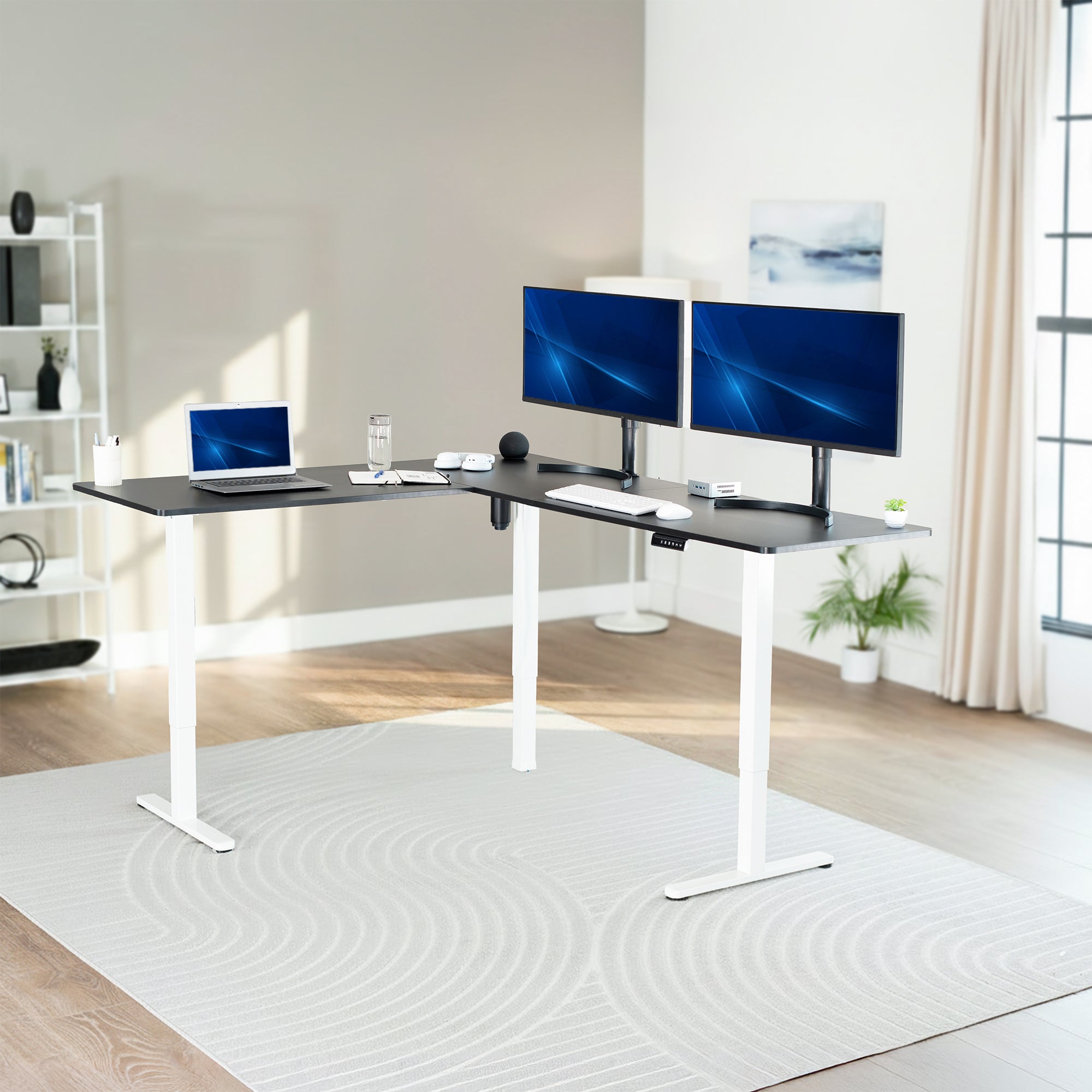 Modern home office setup with a adjustable desk, laptop, and multiple monitors.