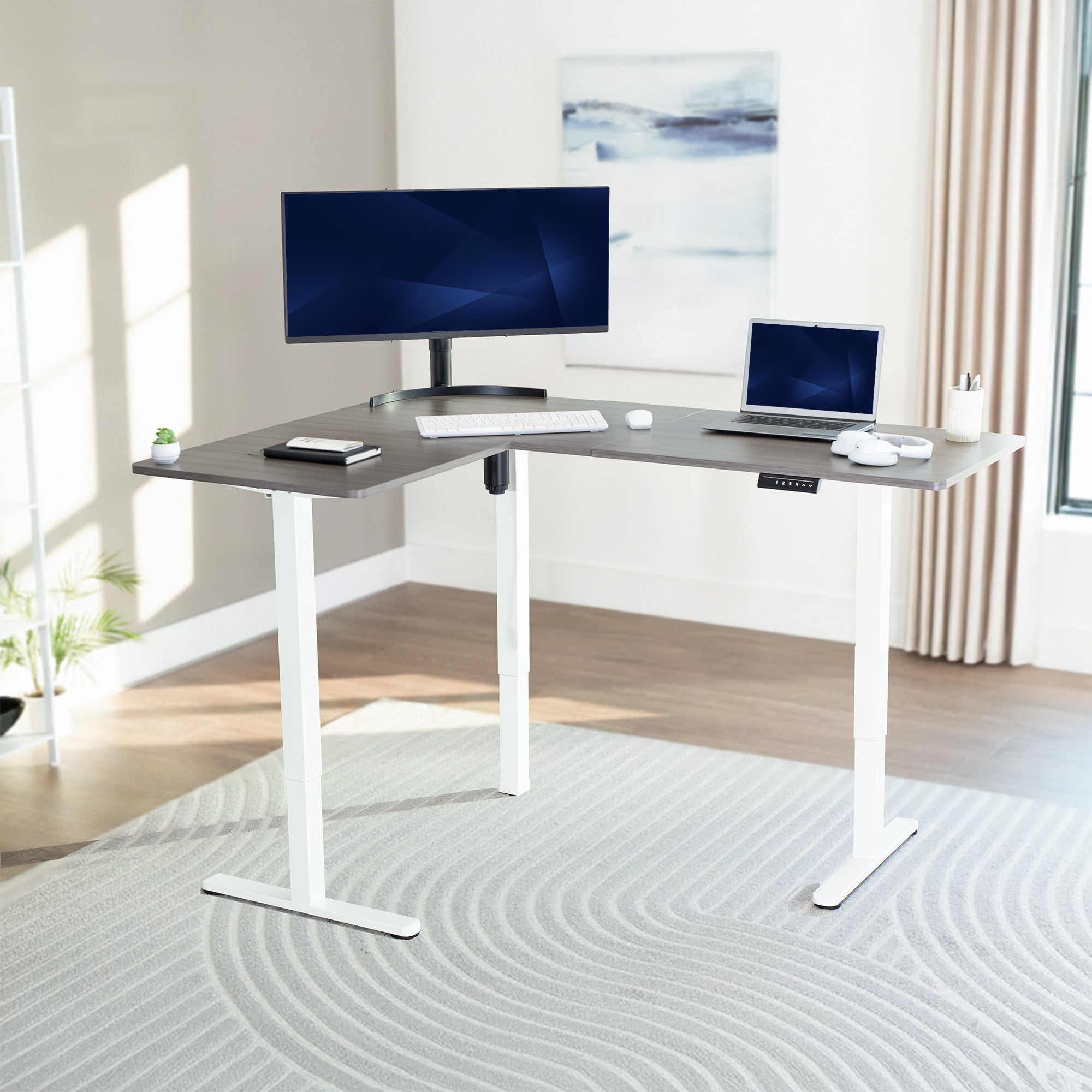 Corner, l-shaped desk with computer setup in a bright room