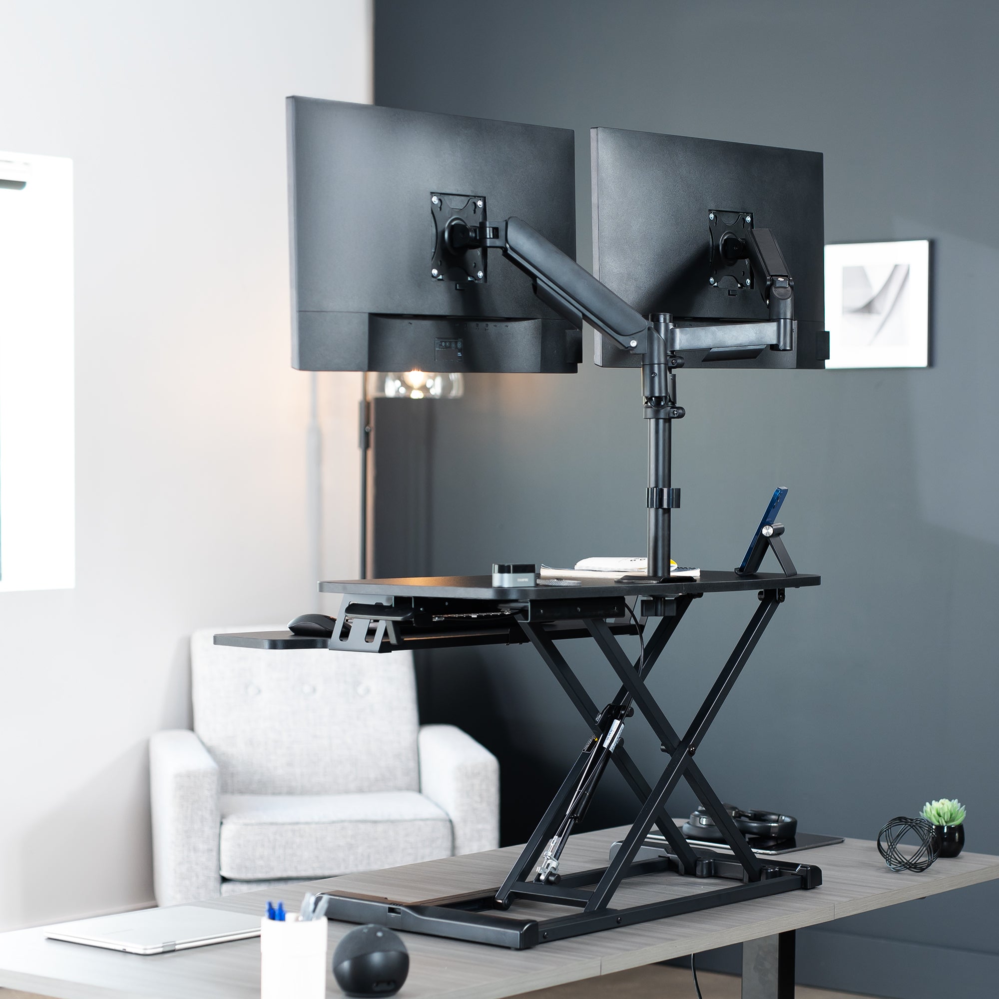 Height adjustable desk riser with articulating mechanical dual monitor mount.