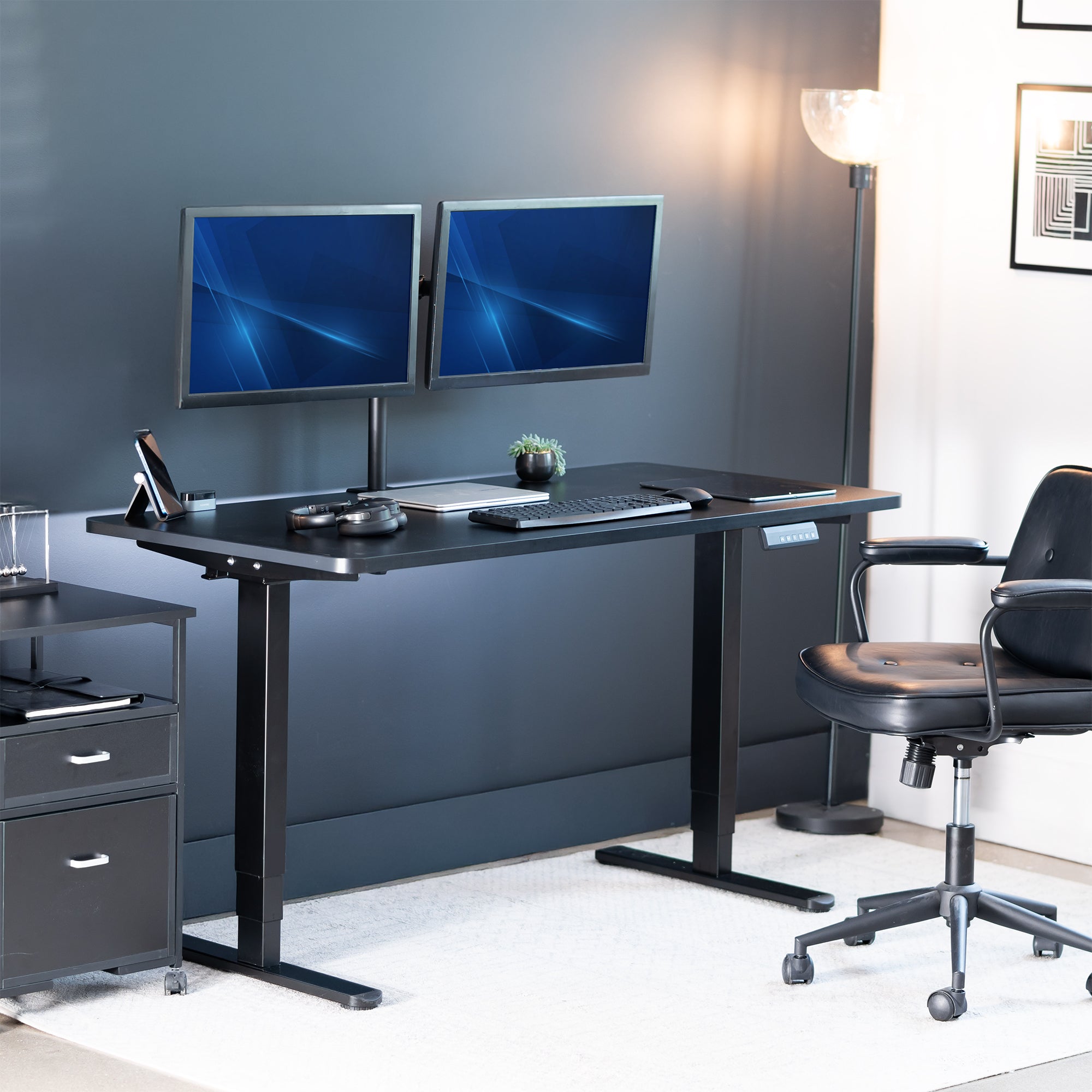 Modern office setup with a black desk, two monitors, and a chair.