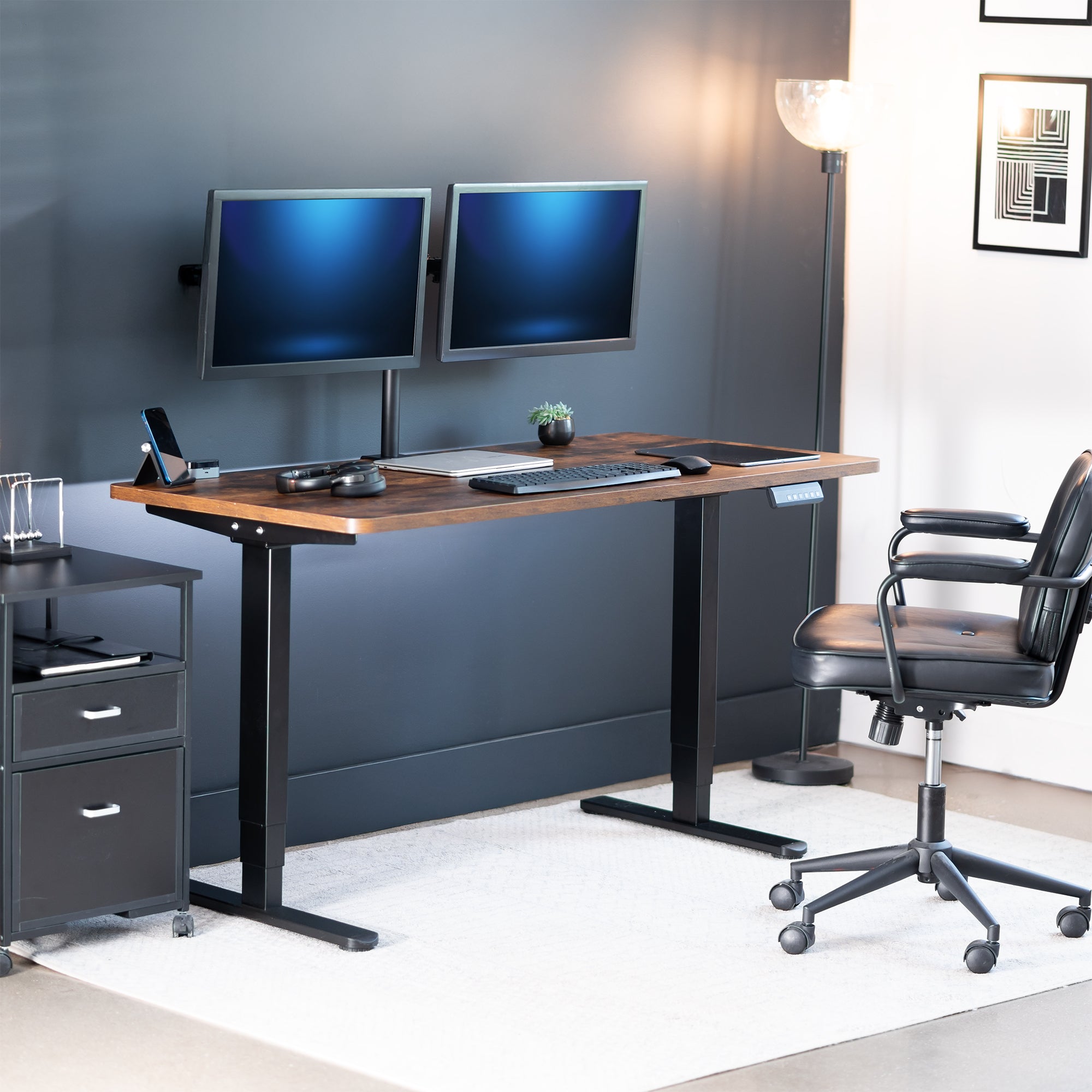 Modern office setup with a standing desk, computer monitors, and office chair.