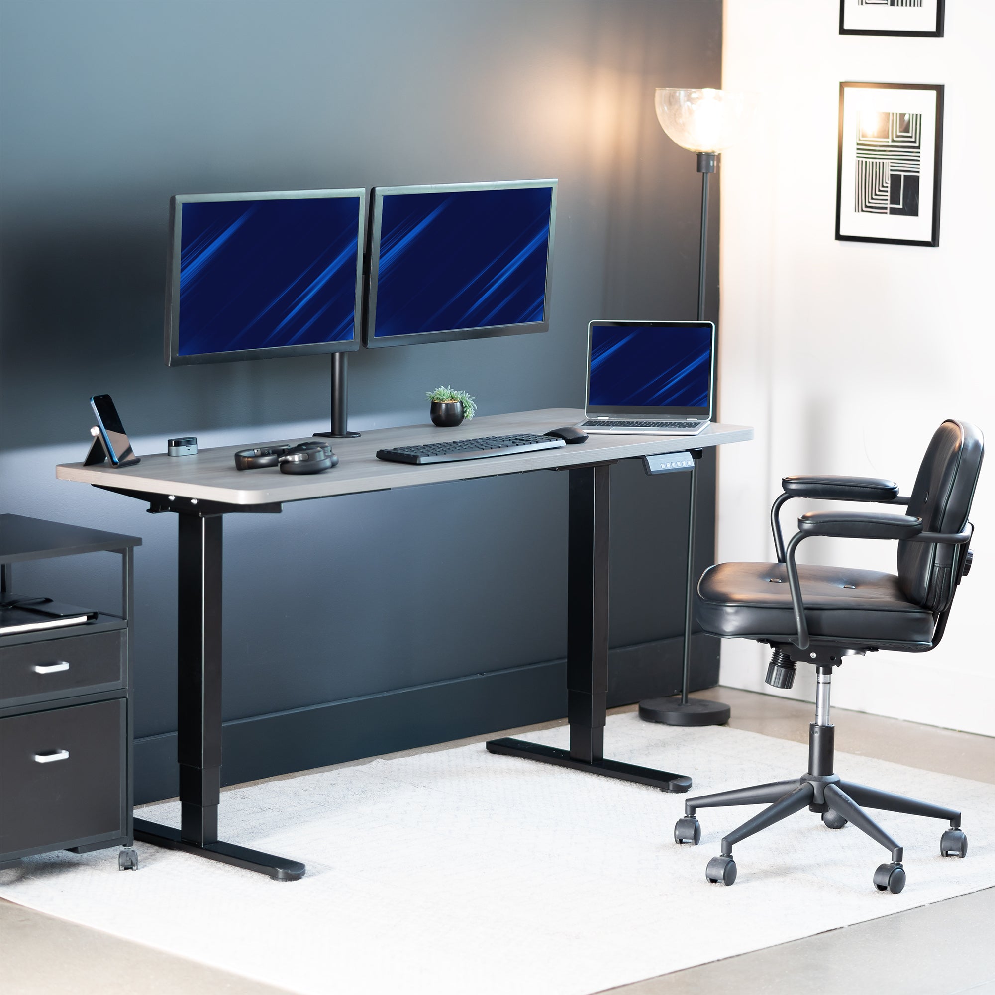 Modern office setup with a standing desk, computer monitors, and a chair.