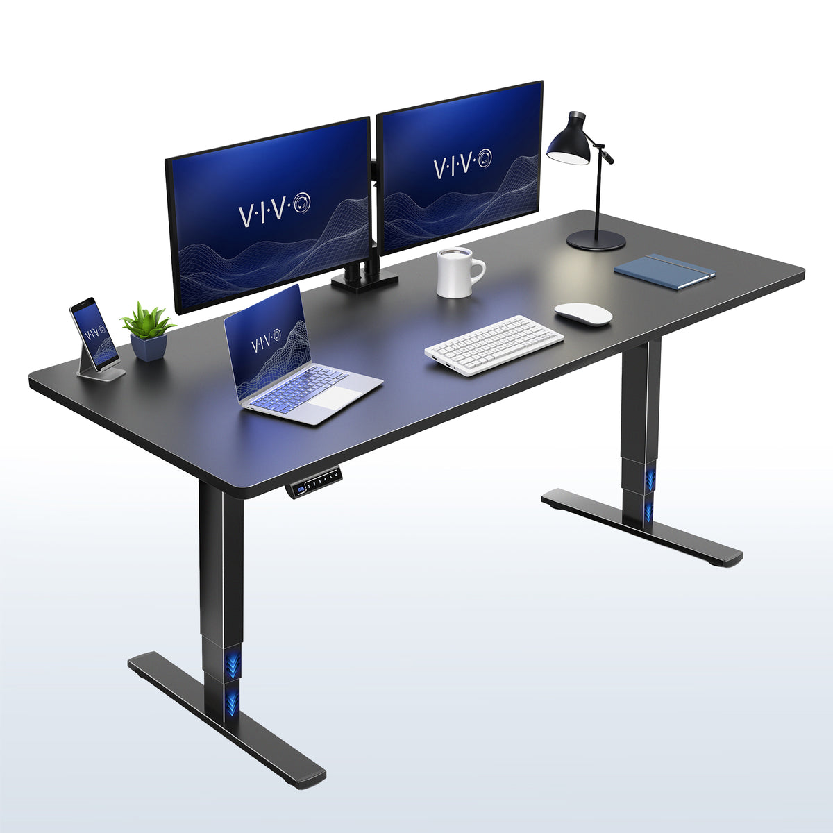 A black modern electric height-adjustable desk with a sleek metal T-style base. The desk is styled with a dual-monitor setup, a laptop, a smartphone on a charging stand, a small potted plant, a white mug, a keyboard, a mouse, and a desk lamp.