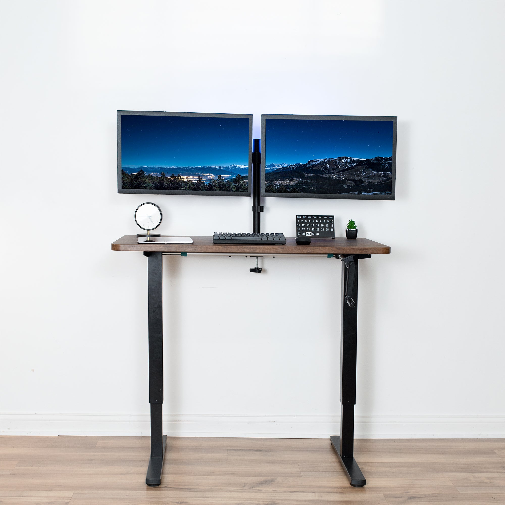 Compact steel desk frame with brown desktop and a dual monitor mount.