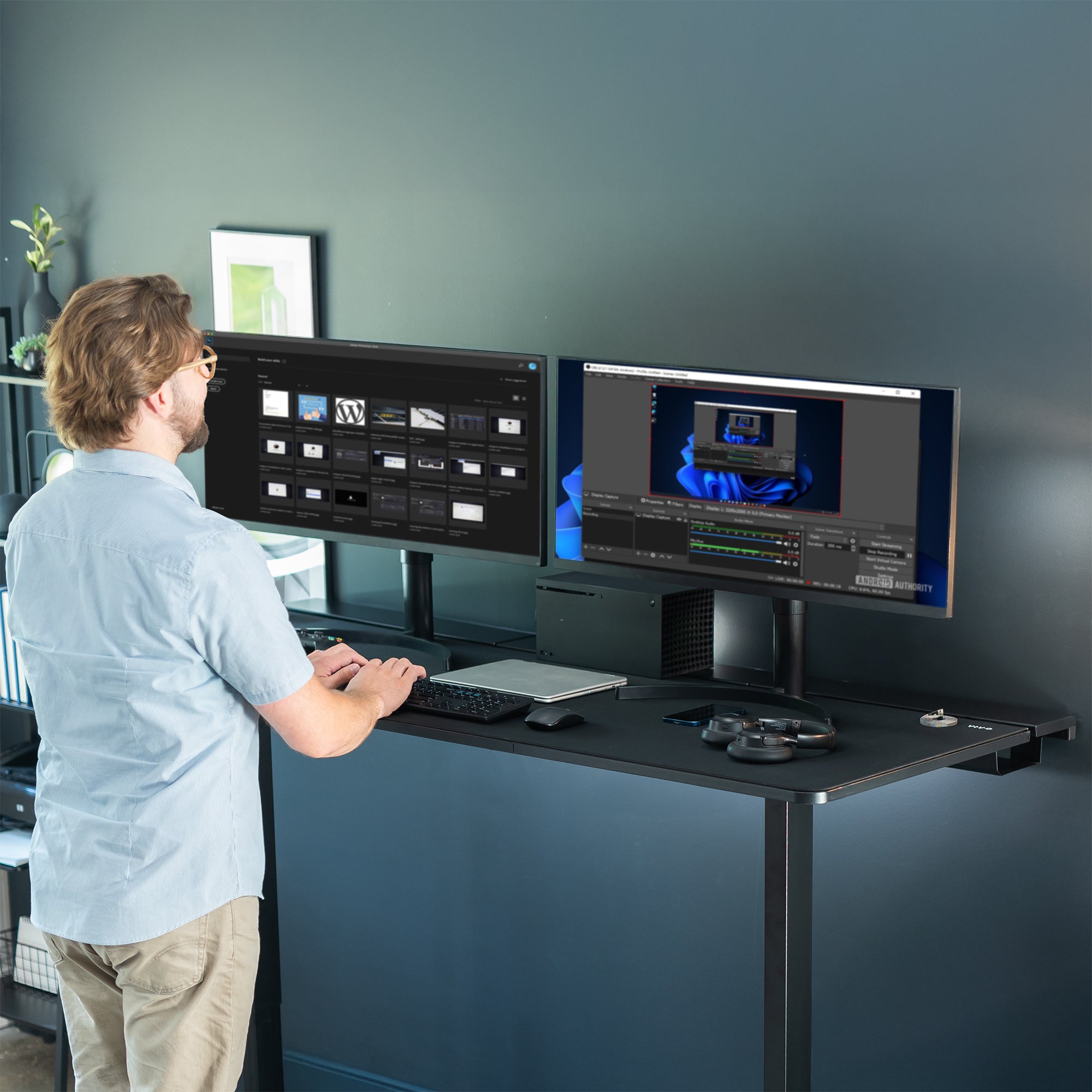 Man working on two monitors on a black desk at ergonomic height