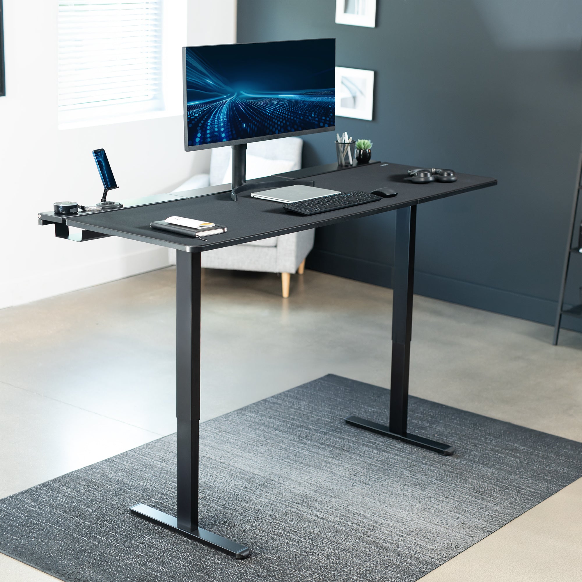 Black adjustable desk with computer setup in a modern office.