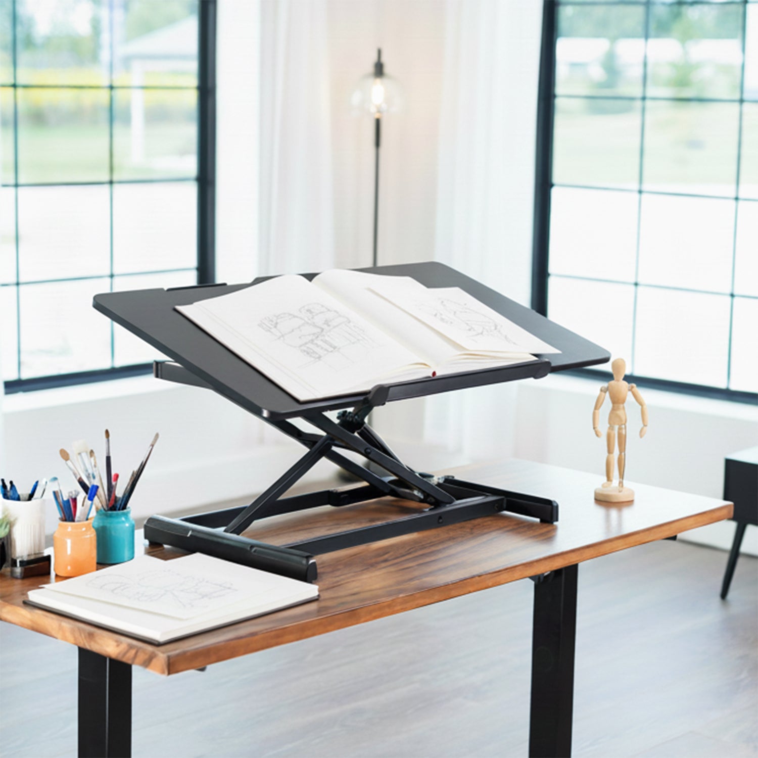 Adjustable standing desk in a bright room with large windows