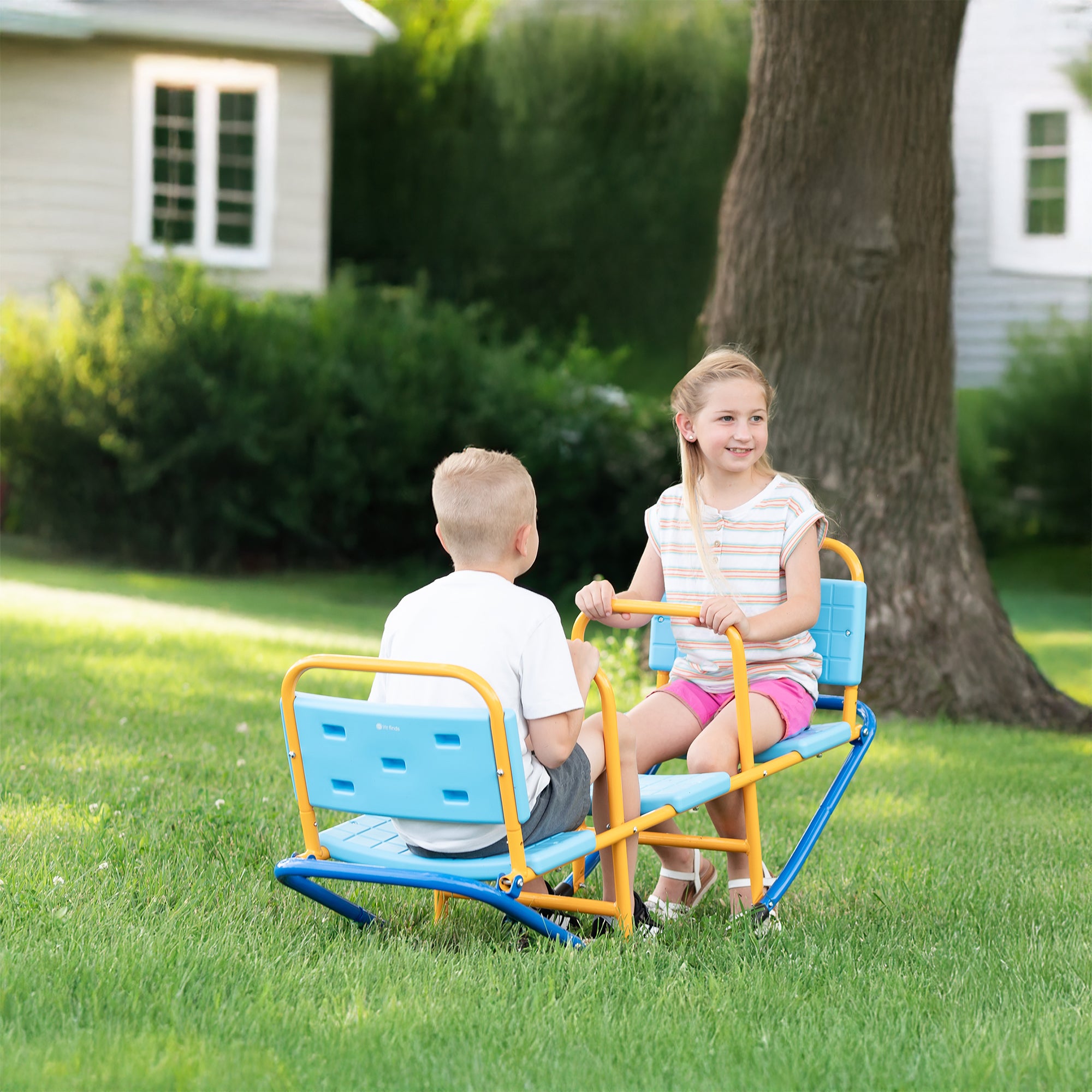 Two children playing on a seesaw in a backyard.