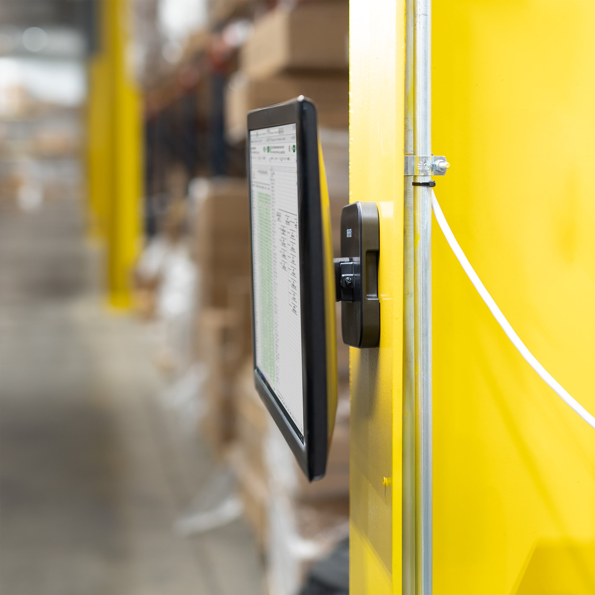 Black metal bracket on a yellow pole in a warehouse.