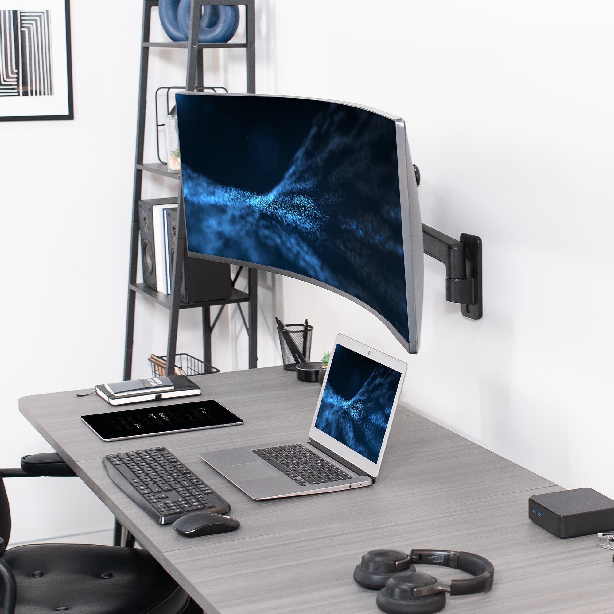 A single ultrawide computer monitor attached to a pneumatic arm wall mount in an office setting.