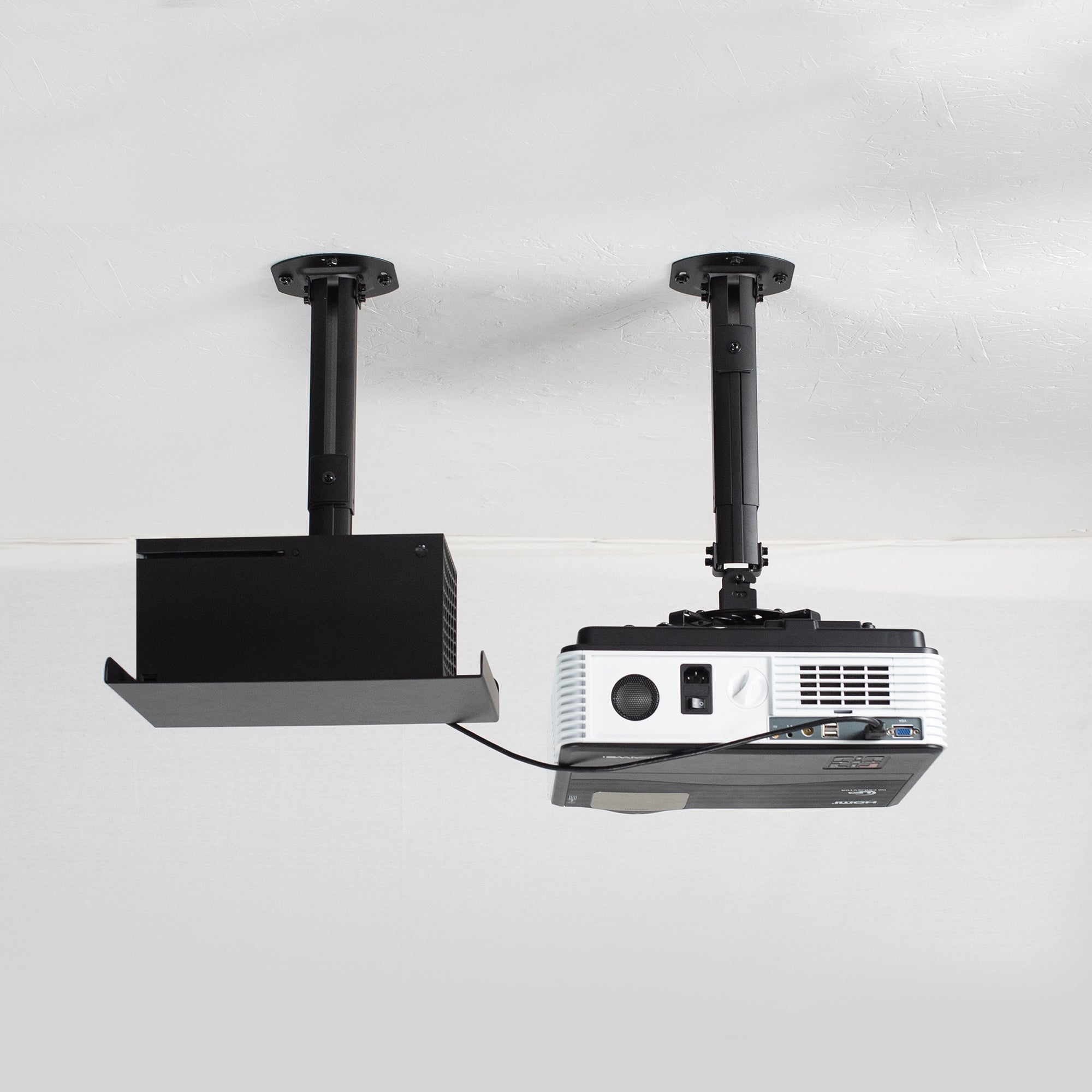 Projector on a ceiling mount next to a speaker shown on ceiling mount with cord connected to the projector