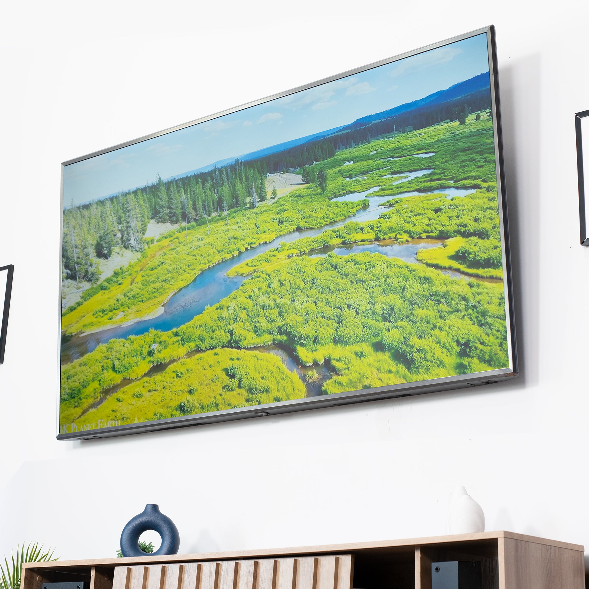 A black tilting wall mount for TVs on a wall with a marsh scene on the screen.