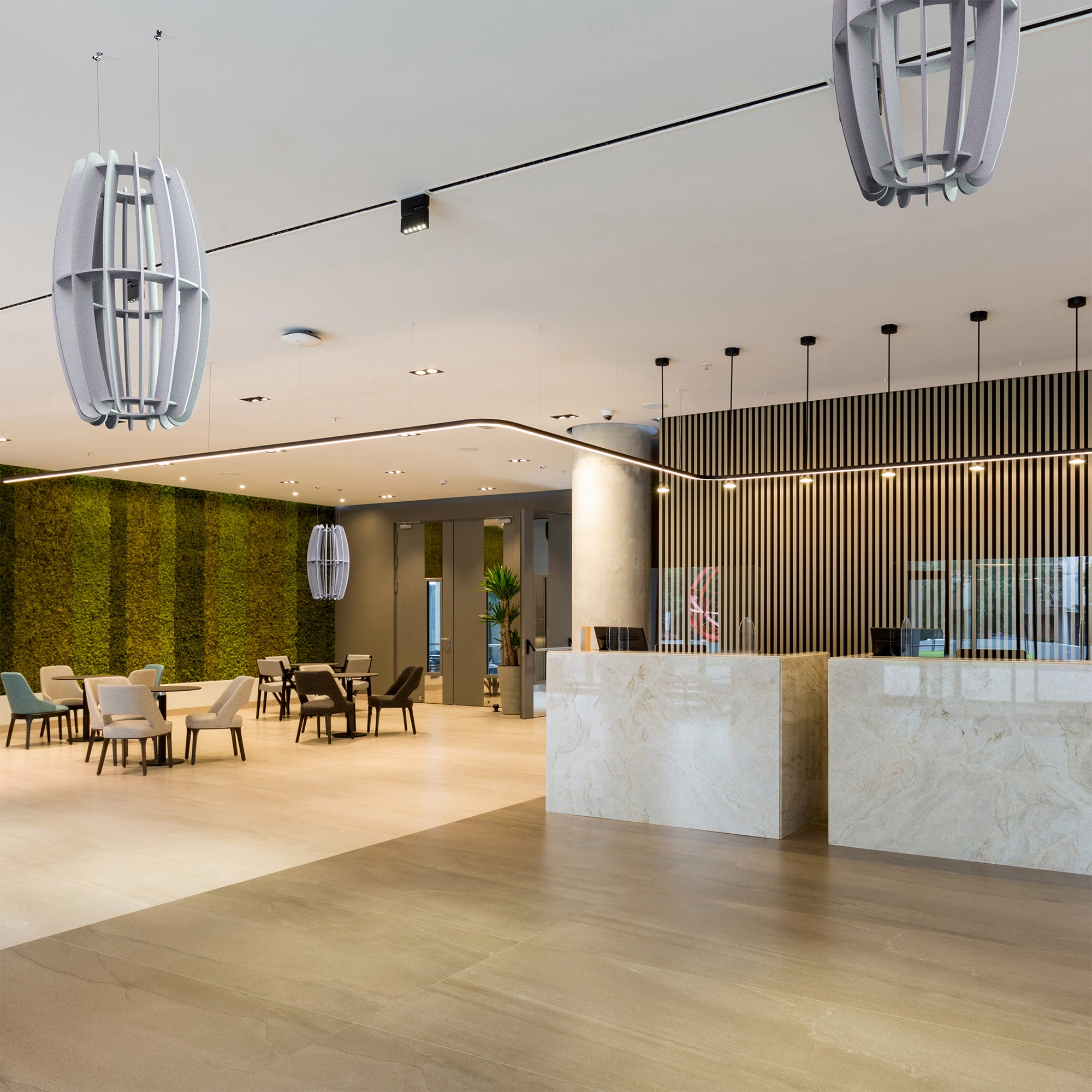 A large oval-shaped acoustic ceiling sound absorber in a light gray color in a minimalist restaurant setting.