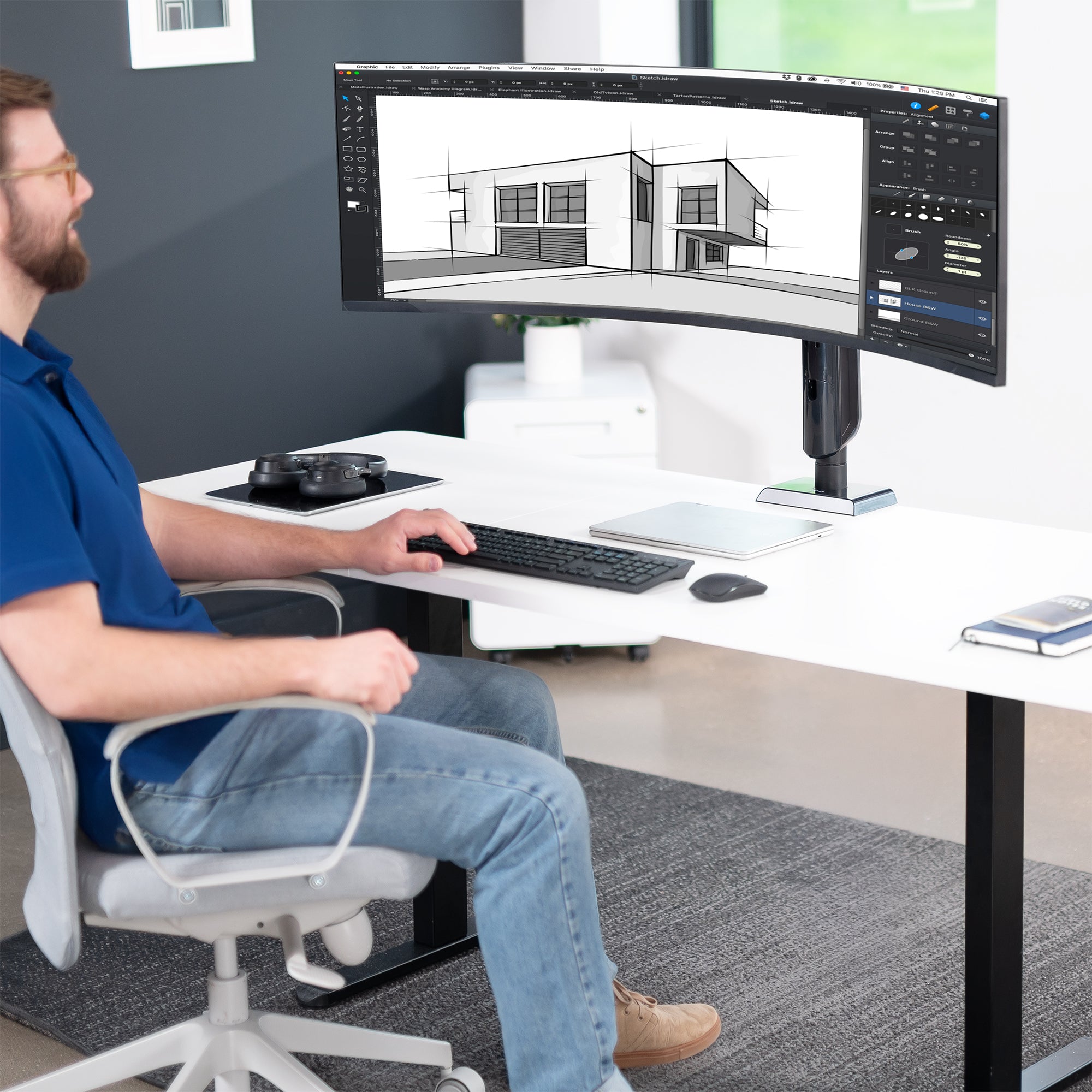 Man sitting at a desk with a single, ultrawide monitor setup, working.