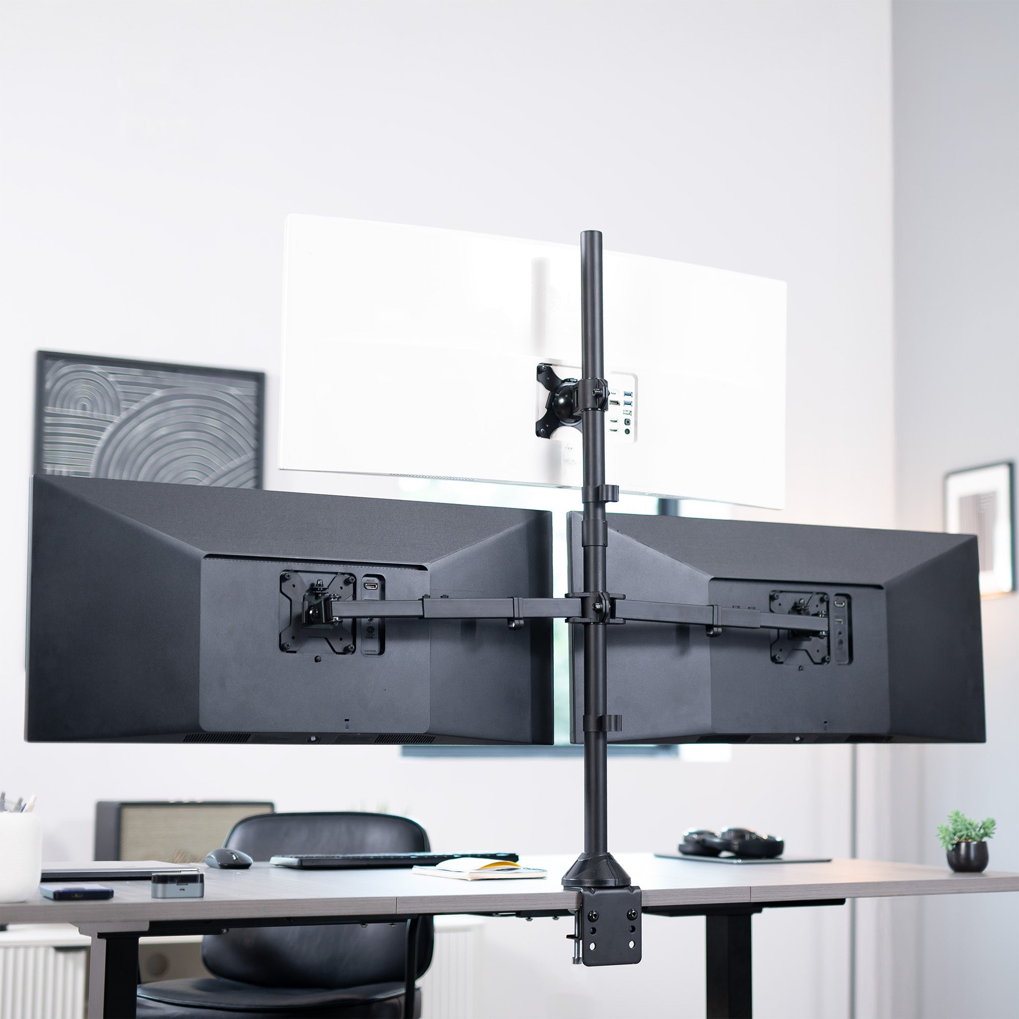 Dual monitor stand on a desk with a blurred office background