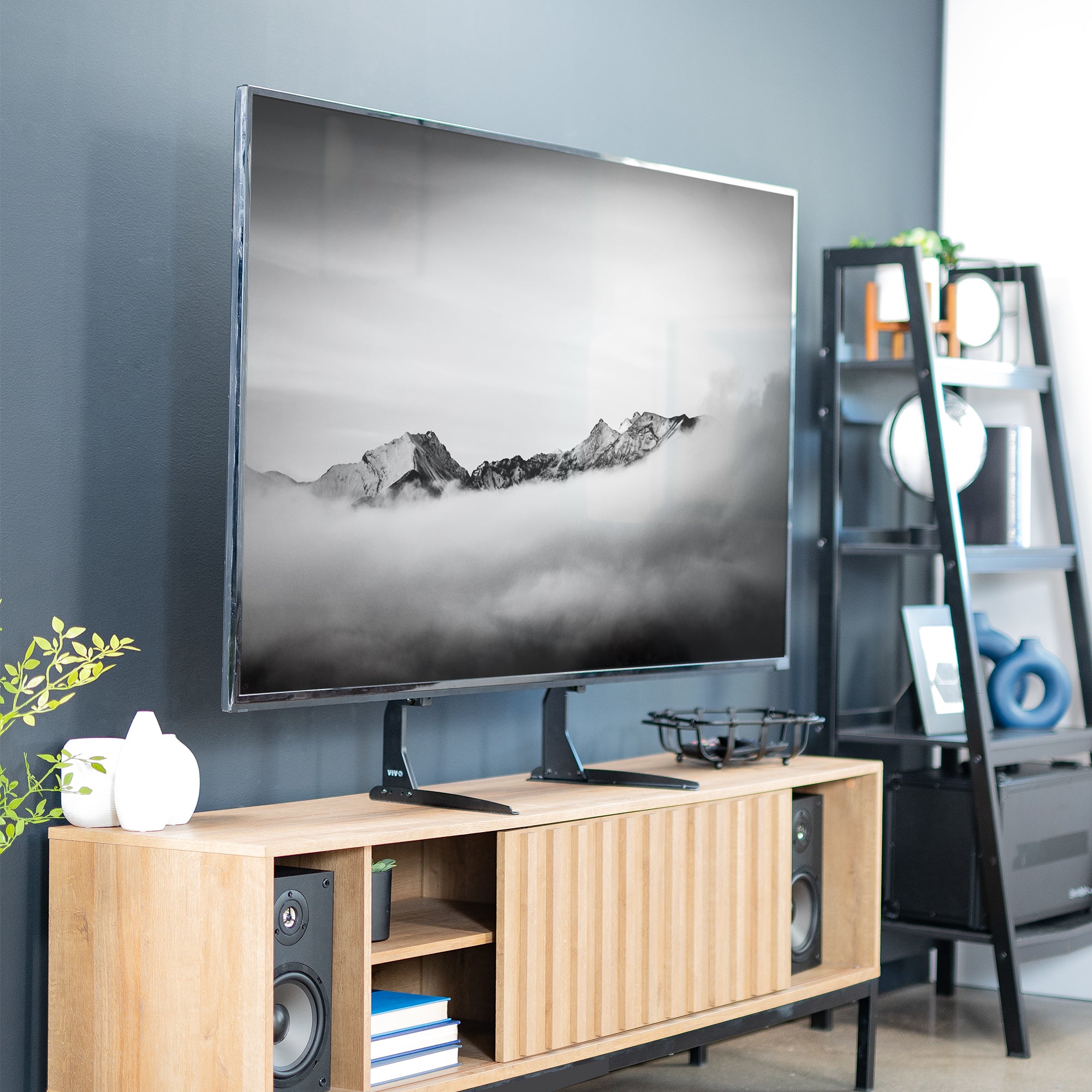 Modern living room with a large TV on a steel stand, speakers, and decorative items.