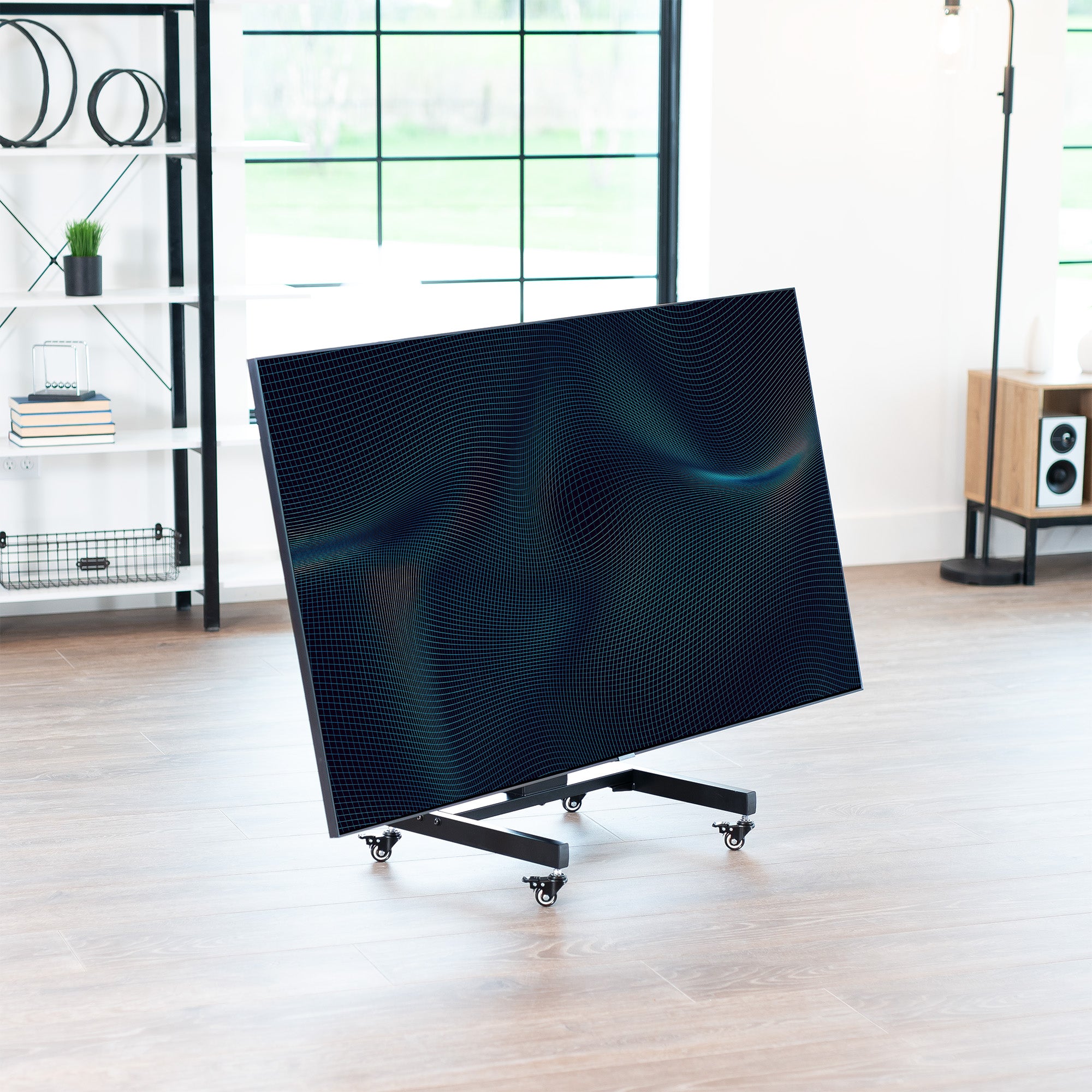 A low height mobile TV cart with a black frame and wheels in a bright room.