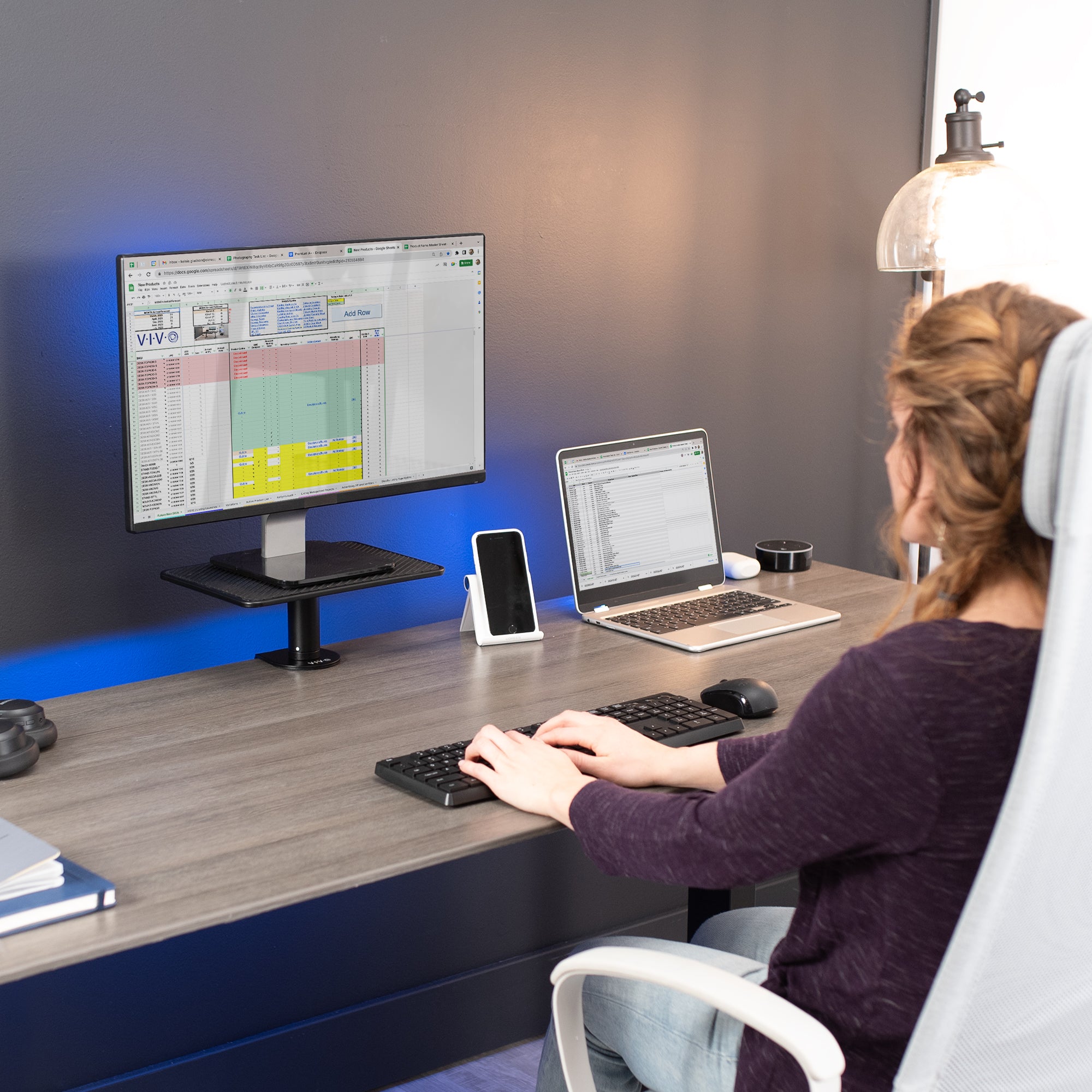 Person working at a desk with a computer and laptop.