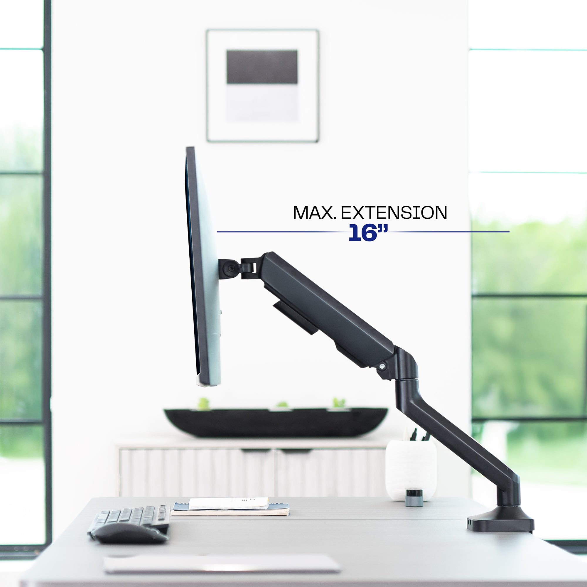 Monitor stand with maximum extension of 16 inches on a desk in an office setting.