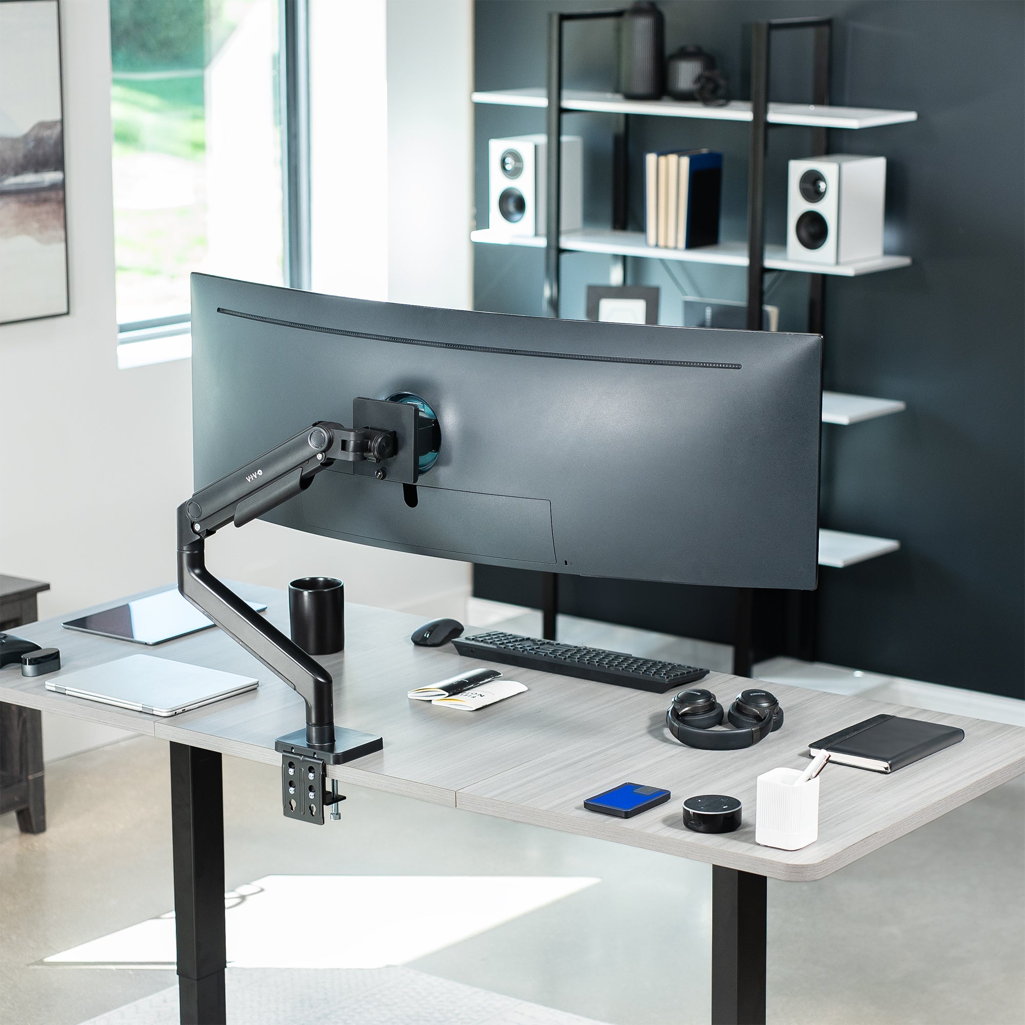 A single ultrawide computer monitor attached to a pneumatic arm desk mount