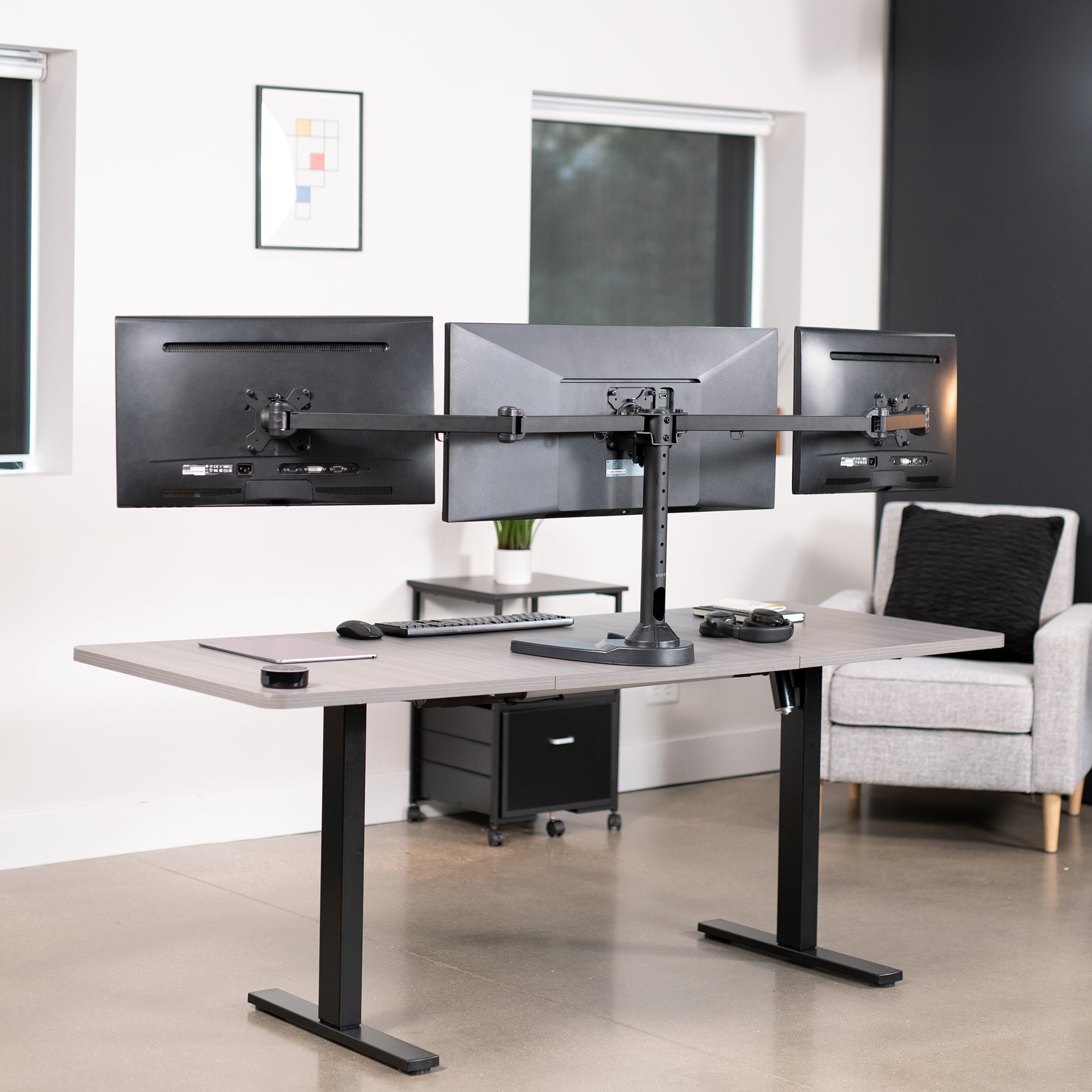 Triple Monitor Desk Stand on desk in office setting.