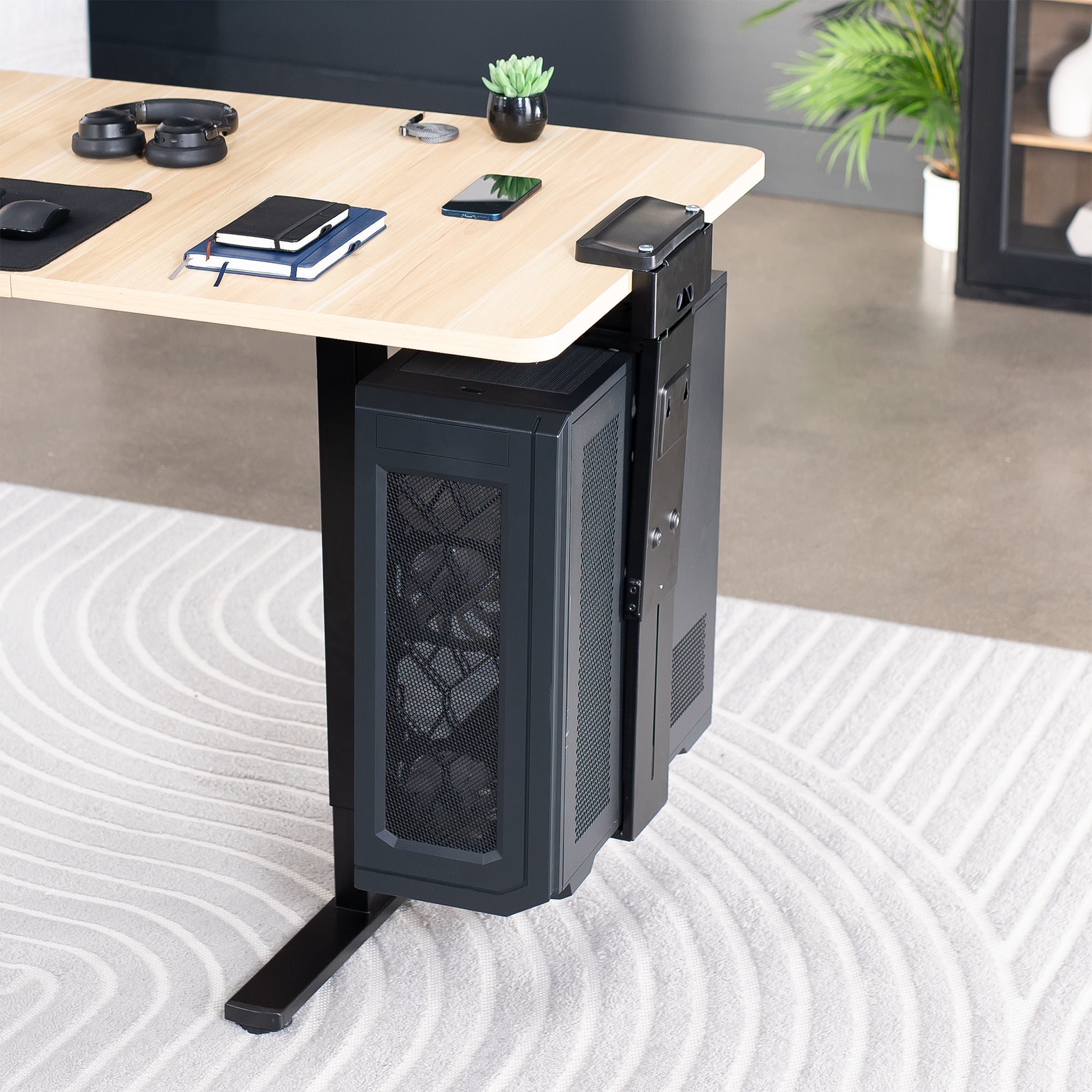 Computer tower mounted under a desk on a clamp-on PC mount in an office setting.