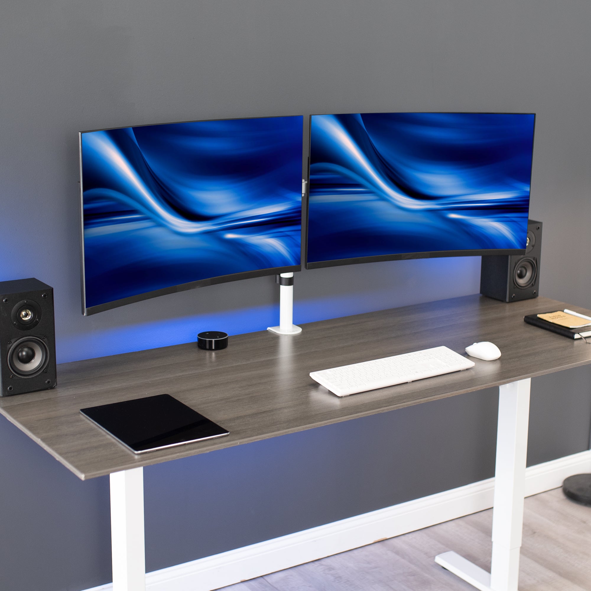 White dual monitor mount on desk in office setting.
