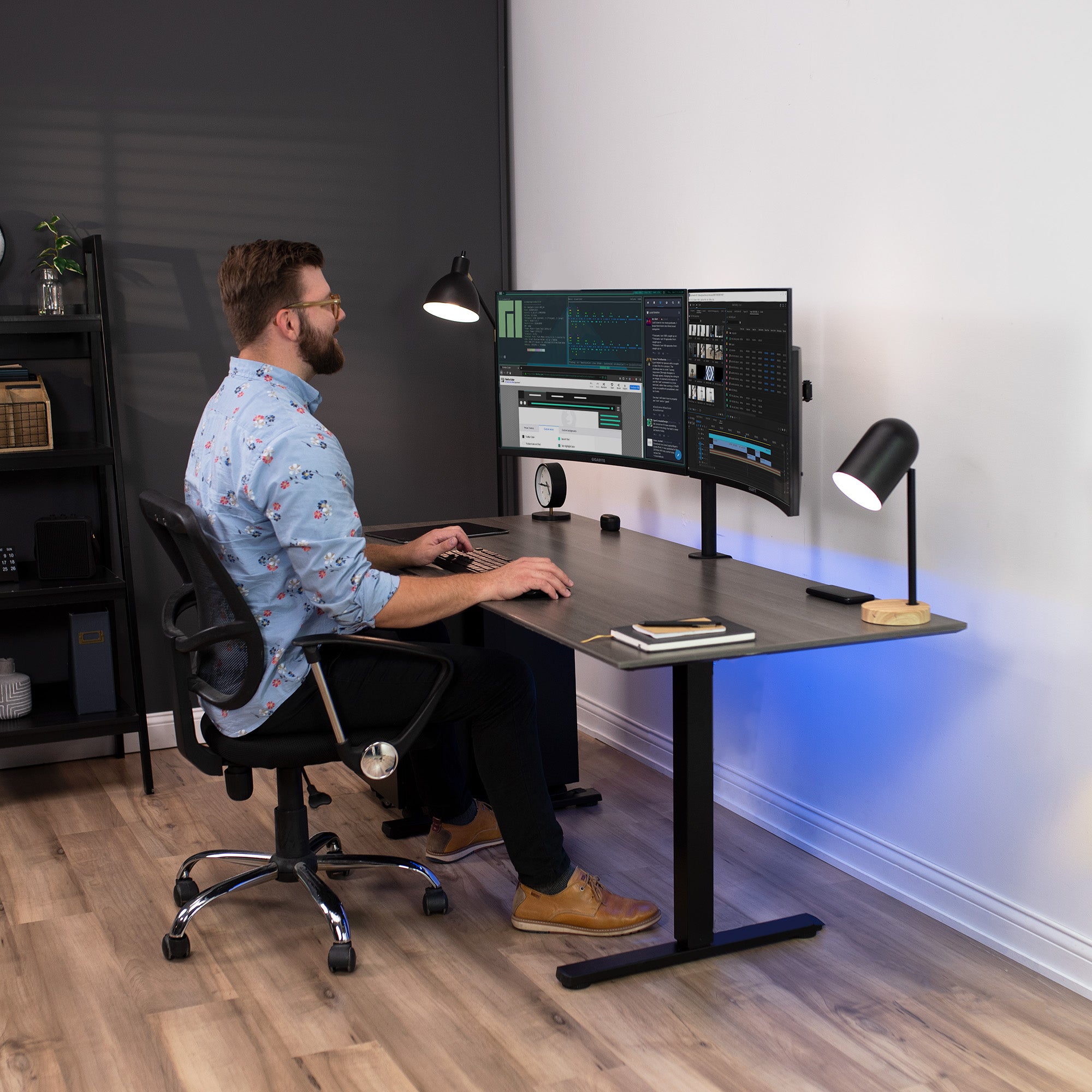 Male model sitting at desk with dual monitor mount.