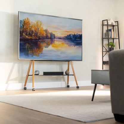 Modern living room with a large TV displaying a nature scene on wooden TV stand, and gray sofa in foreground.