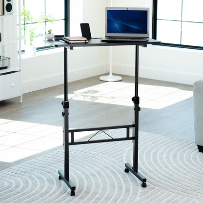 Portable desk with a laptop on a rug in a room with large windows