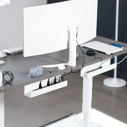 Modern office desk with computer setup and accessories with cable trays under the desk.