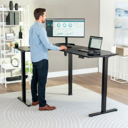 Man using a standing desk with two computer monitors in a home office setting.