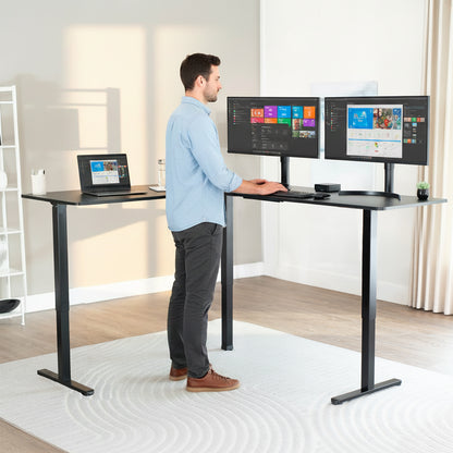 Person using a standing l-shaped corner desk with dual monitors and a laptop.