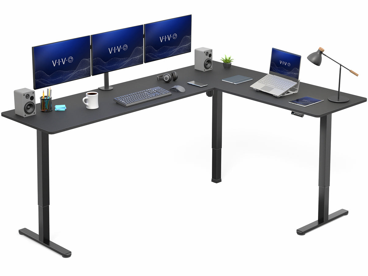 Black L-shaped desk with computer setup including monitors, keyboard, mouse, and laptop on a white background