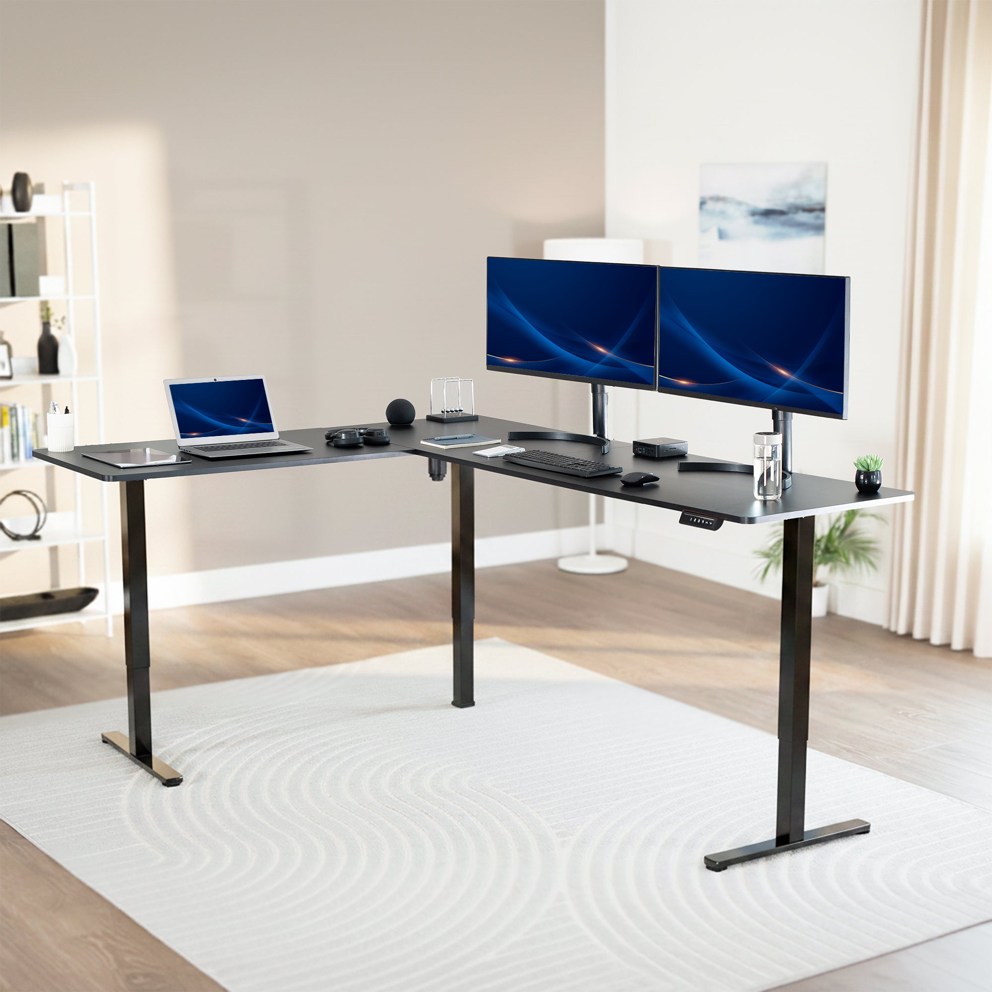 Modern office setup with a black L-shaped desk, dual monitors, and a laptop.