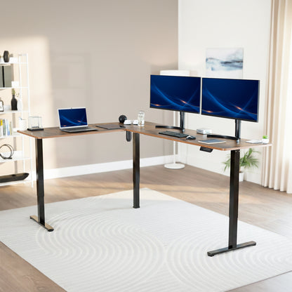 Modern office setup with a standing vintage brown l-shaped desk, laptop, and two monitors in a bright room.