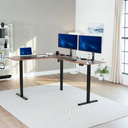 Modern home office with an adjustable standing desk featuring two monitors and a laptop.