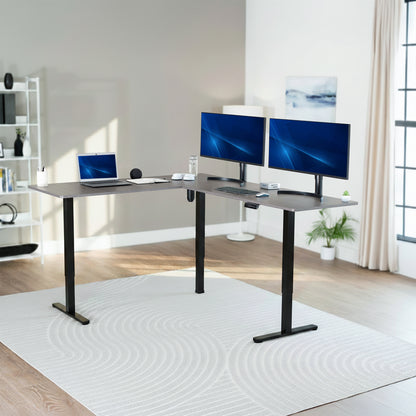 Modern home office setup with a standing l-shaped desk, laptop, and two monitors.
