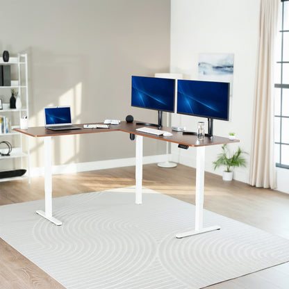 Modern home office with a adjustable L-shaped desk, two monitors, and a laptop.