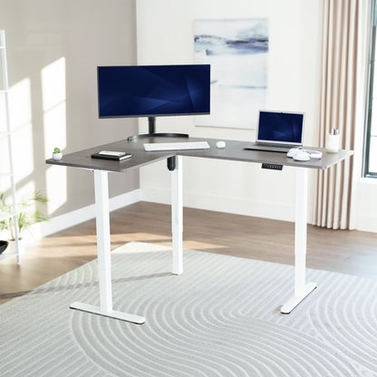 Corner, l-shaped desk with computer setup in a bright room