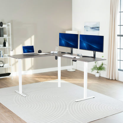 Modern home office with a adjustable l-shaped desk, laptop, and two monitors.