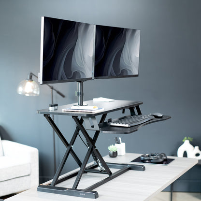 Height adjustable desk riser with articulating pneumatic dual monitor mount.