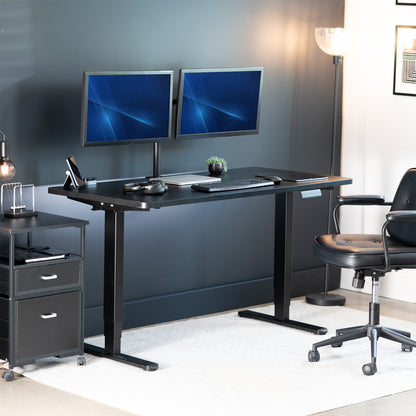 Modern office setup with a black desk, two monitors, a chair, and a lamp.