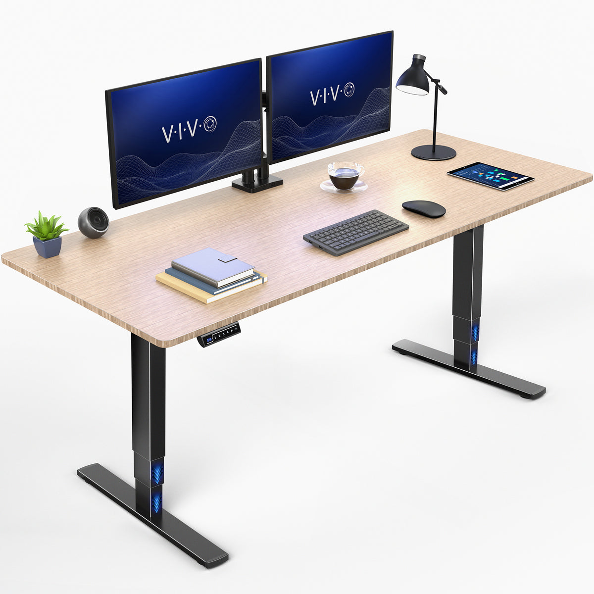 A bamboo adjustable standing desk top and black metal legs, shown with a dual monitor setup, keyboard, mouse, tablet, lamp, books, and a small plant on a clean white background.