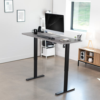 Modern office setup with a adjustable desk, computer monitor, and office supplies.